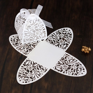 Detailed laser cut white floral gift box with delicate ribbon on a dark wooden surface