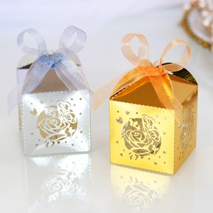 Detail of laser-cut hollow candy boxes with butterfly rose patterns and silk ribbons