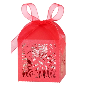 Detailed laser-cut tropical leaf patterns on a vibrant red favor box with silk ribbon