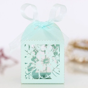 Detailed laser-cut floral pattern on mint green favor box with a silk ribbon bow