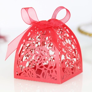 Macro shot of red laser-cut floral candy box with elegant ribbon bow for wedding
