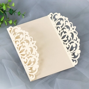 Detail of laser-cut ivory floral invitation cover with intricate hollow scroll patterns