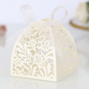 Detail of laser-cut floral pattern on cream wedding favor box with a ribbon bow