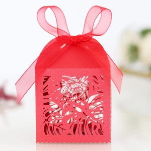Detail of red laser-cut candy box with tropical leaf patterns and ribbon bow