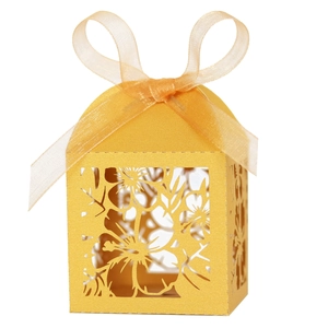 Detail of laser-cut hollow floral pattern on yellow candy box with ribbon bow