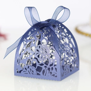 Detail showing navy blue laser-cut floral pattern and ribbon on a wedding favor box