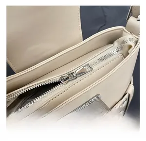 Détail de la boucle métallique argentée et de la fermeture éclair du sac beige
