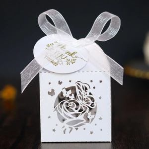 Detail of white laser-cut butterfly wedding favor box with pearl paper and silk ribbon