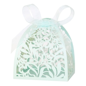 Detail of light blue laser-cut favor box with intricate floral patterns and ribbon bow