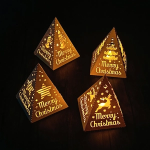 Close-up of four pyramid Christmas paper lanterns with warm LED light and reindeer cutout