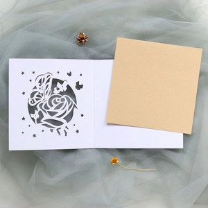 Détails de motifs de roses et papillons découpés au laser sur une carte d'invitation blanche