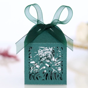 Detail of laser-cut monstera leaf pattern on dark green wedding favors gift box