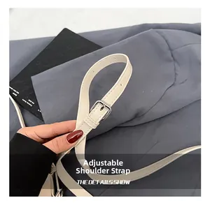 Détail de la bandoulière réglable en cuir crème avec boucle en métal argenté du sac seau