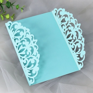 Close-up of laser-cut wedding invitation with intricate floral lace pattern on light blue paper