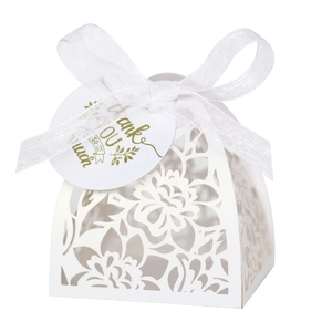 Detail of white laser-cut hollow floral wedding favor box with a silk ribbon and gift tag