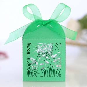 Detail of laser-cut tropical leaf patterns on a green cardstock gift box with ribbon