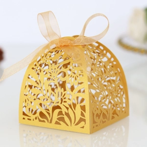 Detail of laser-cut floral pattern on golden gift box with elegant organza ribbon