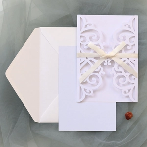 Λεπτομέρεια προσκλητηρίου γάμου laser-cut με ιβουάρ κορδέλα και floral σχέδια