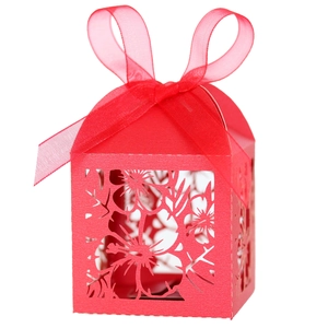 Macro detail of laser-cut cherry blossom patterns on red gift box with silk ribbon