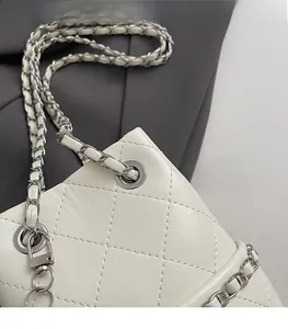 Detail der präzisen Steppung und des silbernen Kettenriemens an der weißen Beuteltasche