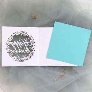 Macro detail of laser-cut butterfly birthday card with turquoise inner paper insert