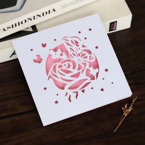 Gros plan d'une carte d'invitation de mariage découpée au laser avec roses et papillon