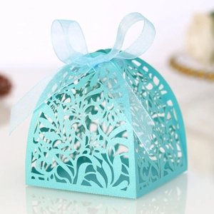 Macro shot of laser-cut hollow pattern on light blue wedding candy box with ribbon