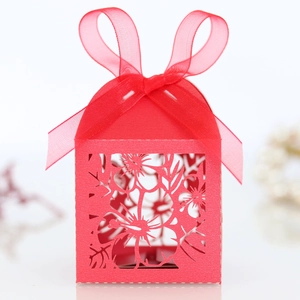 Close-up of red laser-cut candy box with floral hollow patterns and ribbon bow