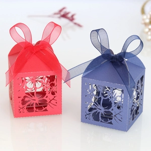 Close-up of laser-cut hollow floral paper candy boxes with elegant organza ribbons