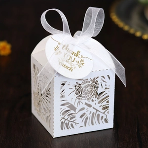 Detail of laser-cut tropical leaf patterns on a white gift box with thank you tag
