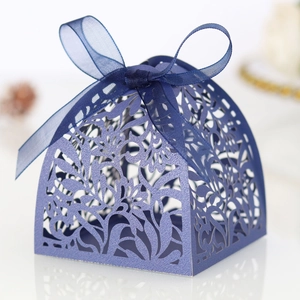 Detailed view of dark blue laser-cut wedding favor box with floral patterns and a silk ribbon