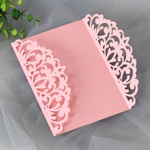 Detail of pink laser-cut wedding invitation cover with intricate lace flower patterns