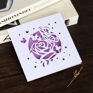 Détail d'une carte de mariage découpée au laser avec roses, papillons et insert violet