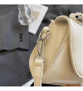 Detailed view of silver metal hardware and smooth cream synthetic leather side profile
