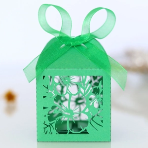 Close-up of laser-cut hollow floral pattern on light green candy box with ribbon