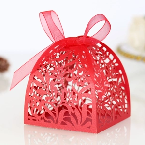Close-up of red laser-cut floral wedding favor box with a delicate red satin ribbon bow