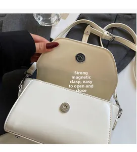 Detail view of the strong magnetic buckle on white PU leather shoulder bag for easy closure