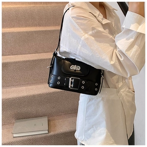 Détail du sac bandoulière en cuir noir avec œillets argentés porté par un mannequin