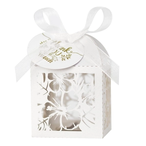 Detail of white laser-cut floral candy box with silk ribbon and golden thank you tag