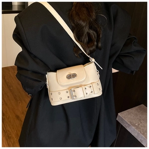 Détail du sac seau crème avec œillets métalliques et bandoulière sur l'épaule