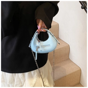 Detail of light blue textured leather handbag featuring chain strap and top handle