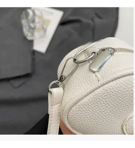 Detail of silver zipper and metal hook on white lychee grain leather shoulder bag