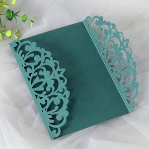 Detail of dark green laser-cut wedding invitation sleeve with elegant floral patterns