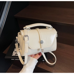 Detailed macro view of the cream white faux leather texture and silver buckle on the mini bag