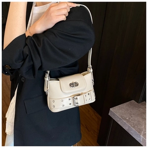 Détail du sac à bandoulière crème avec fermoir rotatif argenté et ceinture à œillets