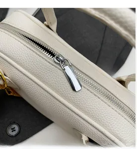 Close-up of smooth silver metal zipper on white litchi textured leather handbag