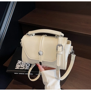 Close-up of cream crossbody bag featuring a silver circular buckle and fine PU leather texture
