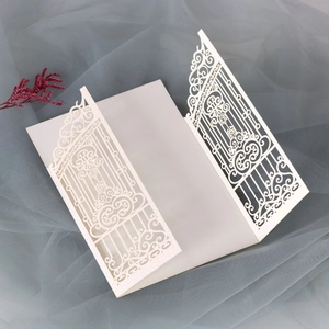 Detail of laser-cut ivory wedding invitation with intricate gate patterns and shimmer finish