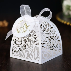 Detail of white laser-cut wedding favor box with floral patterns and a thank you tag