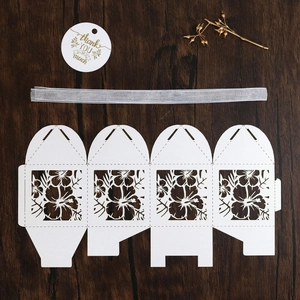 Flat lay of laser-cut gift box DIY kit with white floral patterns and thank you tag
